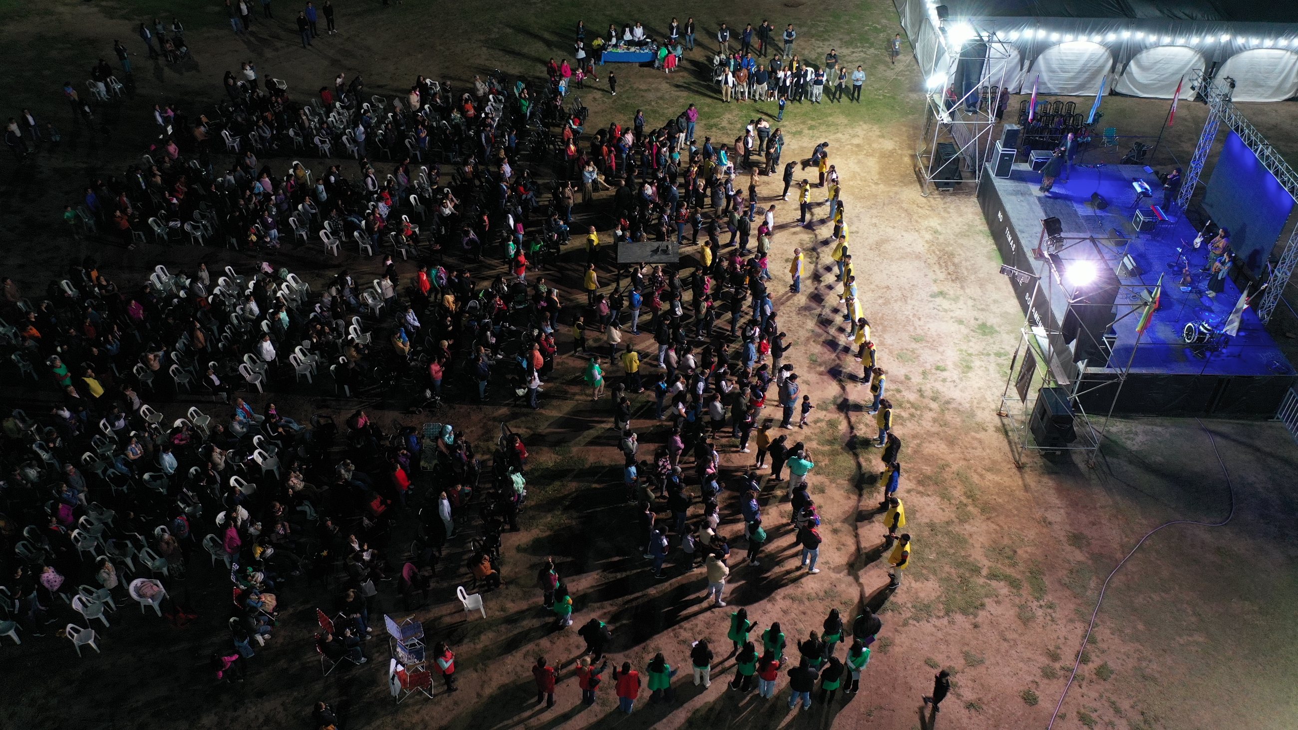 Vista aérea nocturna de multitud reunida en campaña