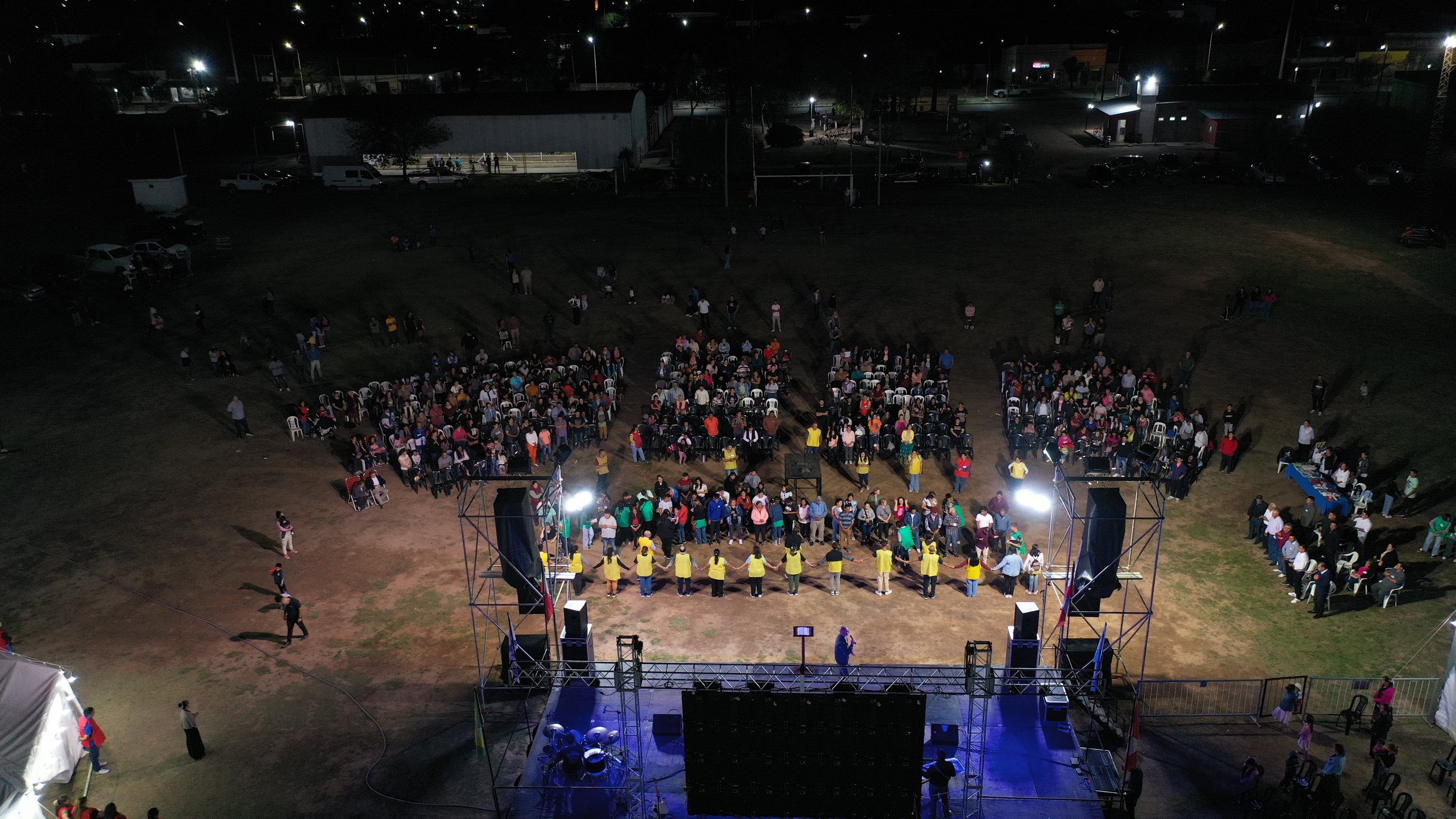 Vista aérea de multitud y escenario durante campaña nocturna