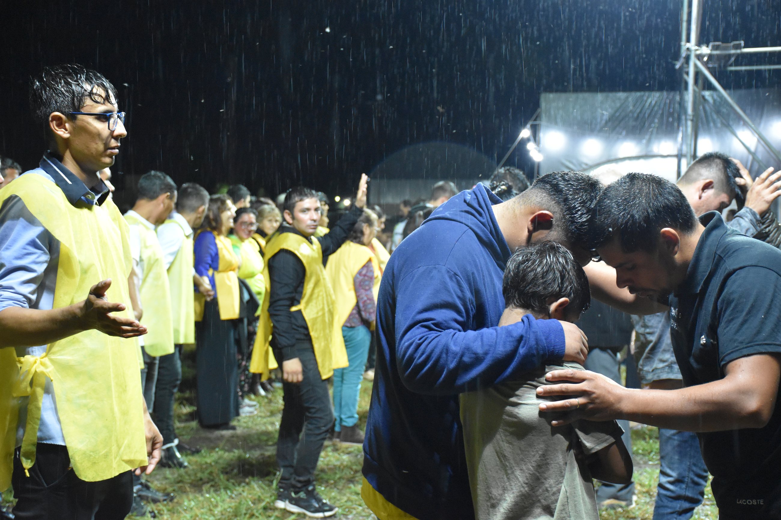 Momento emotivo de oración bajo la lluvia durante campaña evangelística